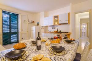 a kitchen with a table with food and a bottle of wine at Villetta Grecale Porto Cesareo in Porto Cesareo +21 photos