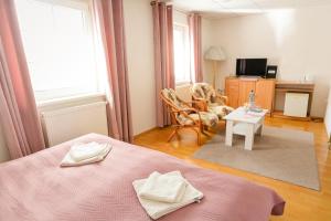 a bedroom with a pink bed and a living room at Penzion Romantik in Dolná Streda