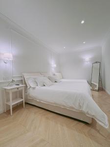 a white bedroom with a large bed and a table at DIMORA CARDUCCI in Bari