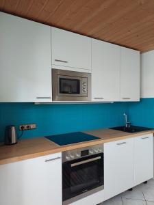 a kitchen with white cabinets and a microwave at Häuschen Kunterbunt in Mittenwald +22 photos