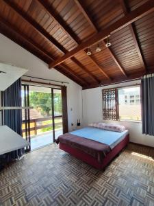 ein Schlafzimmer mit einem Bett und einem großen Fenster in der Unterkunft Casarão até 8 pessoas 400m mar Bombinhas in Bombinhas