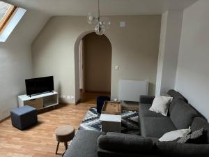 a living room with a couch and a tv at Beau duplex proche centre in Kaysersberg