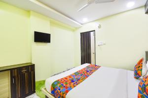 a bedroom with a bed and a tv on the wall at FabHotel Galaxy Shamshabed - Nr Hyderabad International Airport, Shamshabad in Shamshabad +29 photos