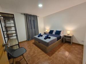 a bedroom with a bed with blue pillows and a ladder at Autonomia House II in Câmara de Lobos