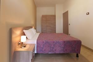 een slaapkamer met een bed en een tafel met een lamp bij Residence Kalispera in Scalea