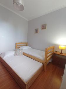 two beds in a room with a lamp and a table at Village Sea House - Porto Moniz in Porto Moniz