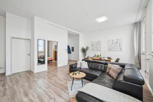 a living room with a black leather couch and a table at Yello Homes - Loft - Airport & Messe 6 Betten & Wifi in Nürnberg