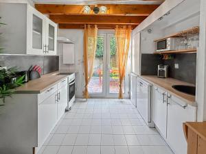 ヴィック・ラ・ガルディオルにあるMaison de vacances lumineuseの白いタイルフロアのキッチン(白いキャビネット付)