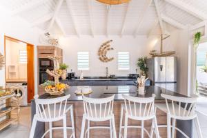 a kitchen with white chairs and a table with a counter at Villa Bohème in Terre-de-Haut