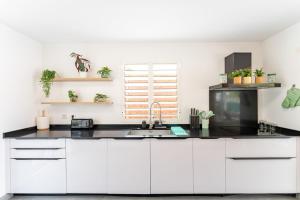 a kitchen with white cabinets and black countertops at Villa Opale in Terre-de-Haut