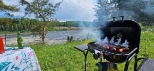 a grill with hot dogs on it next to a river at Hammarstrandvilla in Hammarstrand