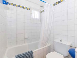 e bagno con vasca, servizi igienici e tenda per la doccia. di Villa Es Cantell a Binisafua Altre 37 foto