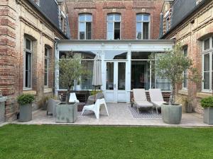 a patio with chairs and tables in front of a building at Hôtel Particulier Petit-Decaix in Conty