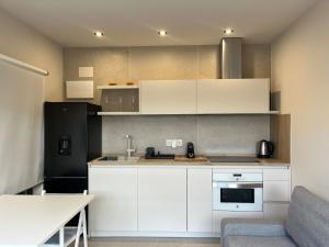eine Küche mit weißen Schränken und einem schwarzen Kühlschrank in der Unterkunft Beautiful renovated studio in Castelldefels