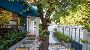 a tree on a sidewalk next to a building at Shade House - Bitec Bangna in Bangkok