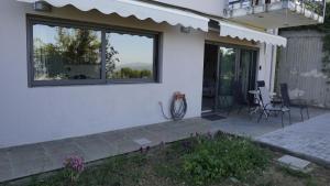 una casa bianca con un patio con sedie e finestre di Romanos Patras studio a Patra