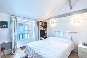 a bedroom with a white bed and a window at Appartement Verdun - Welkeys in Biarritz
