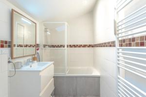 a bathroom with a sink and a tub and a mirror at Appartement Verdun - Welkeys in Biarritz