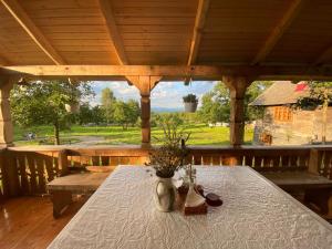 a wooden porch with a table with flowers on it at Poiana Creasta Cocosului-Casa Papadie in Breb