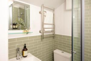 a bathroom with green subway tiles and a toilet at Bob W London Holland Park in London +55 photos