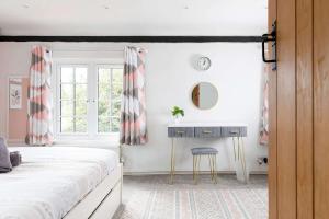 a bedroom with a bed and a desk and a window at Tranquil Luxe in Country Cottage in Bosham