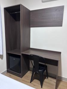 ein hölzerner Schreibtisch mit einem schwarzen Stuhl in einem Zimmer in der Unterkunft Otto Hotel in Governador Valadares
