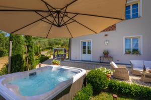a hot tub in a backyard with an umbrella at Villa Regina, 4 bedrooms and a luxury style villa in Cappella