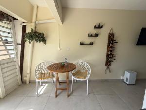 a dining room with a wooden table and two chairs at L Opacarophile Studio Marina du Gosier in Le Gosier