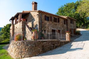 a stone house with a fence in front of it at Villa Beatrice - Private Heated Pool & Amazing Umbrian Landscape in Corgna