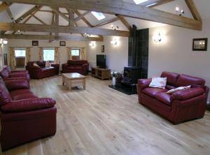 a living room with leather couches and a tv at Bed & Breakfast at Newton House Farm in Sneaton