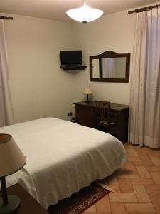 a bedroom with a bed and a desk and a mirror at Hotel Ristorante Il Cavaliere in Camerino