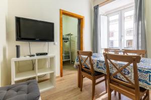 a living room with a television and a table with chairs at Alfama Very Well-Connected Apartment in Lisbon