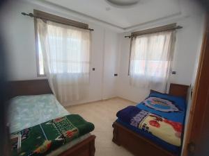 a bedroom with two beds and two windows at Future in Taghazout