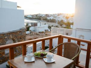 a wooden table with a bowl of fruit on a balcony at Dafnis Koufonisia in Koufonisia