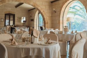 a dining room with white tables and chairs with white table linen at Tenuta Masseria & Spa Chicco Rizzo in Sternatia