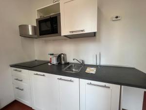 a kitchen with white cabinets and a black counter top at Vista Cupola House in Rome