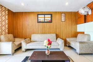 FabHotel Shreyas Shack في Kammasandra: غرفة معيشة مع كرسيين و مزهرية ورد على طاولة