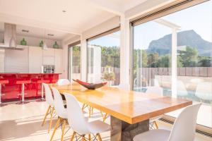a kitchen and dining room with a wooden table and white chairs at Villa Montfarrutx in Colonia de Sant Pere
