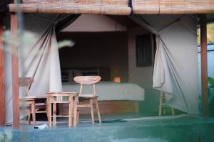 two chairs and a table and a bed in a room at The Breeze Glamping in Bangli