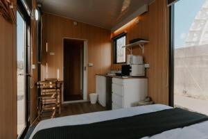 a bedroom with a bed and a kitchen with a microwave at Fulu Dragon Boat Camping House 2 by Tiny Away in Ch'iao-t'ou