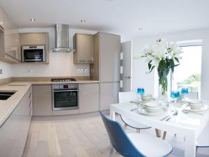 a white kitchen with a white table and chairs at 7 Atlantic Watch in St Ives