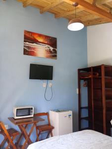 a bedroom with a bed and a table and a tv at Hibisco Rosa Aluguéis in Araçatuba