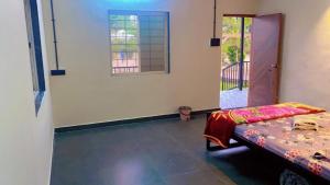 a room with a bed and a window and a door at Shantai Farms in Talegaon Dābhāde