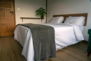 a bedroom with a large bed with white sheets at Pousada Monttana in Lavras Novas
