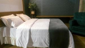 a bedroom with a white bed and a blue chair at Pousada Monttana in Lavras Novas