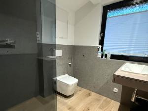 ein Badezimmer mit Toilette und Waschbecken und einem Fenster in der Unterkunft Holzhaus am Listersee in Windebruch
