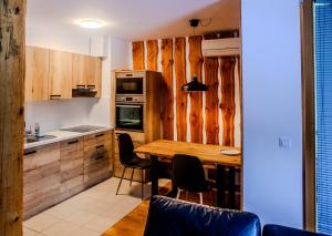 a kitchen with wooden cabinets and a wooden table at APARTMA JEREBIKA ŠT. 20 in Hočko Pohorje