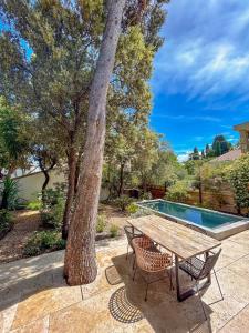 un tavolo e sedie seduti accanto a un albero di Villa Rethel avec piscine - dans le centre de Montpellier a Montpellier