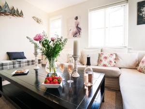 ein Wohnzimmer mit einem Couchtisch mit Blumen und Kerzen in der Unterkunft Cannon Corner by The Suffolk Cottage Collection in Aldeburgh + 12 Fotos