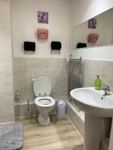 a bathroom with a toilet and a sink at Stanton - Stylish 2 Bedroom in Dagenham
